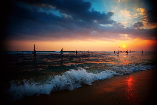 Silhouettes of the traditional stilt fishermen at the sunset near Galle in Sri Lanka