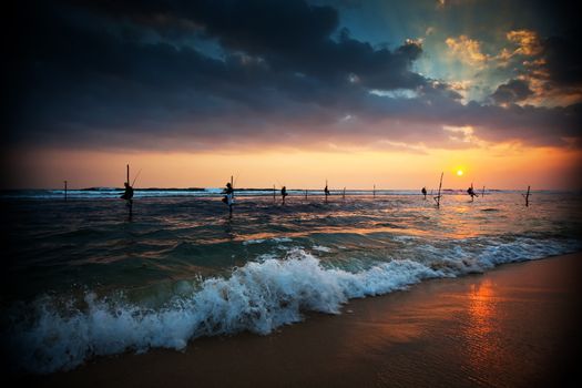 Silhouettes of the traditional stilt fishermen at the sunset near Galle in Sri Lanka