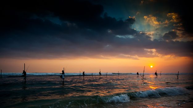 Silhouettes of the traditional stilt fishermen at the sunset near Galle in Sri Lanka