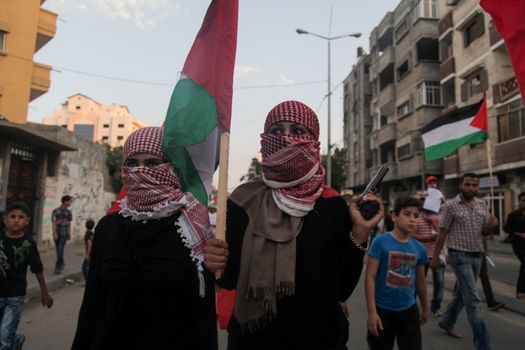 GAZA, Gaza City: A member of the Popular Front for the Liberation of Palestine holds a gun and Palestinian flag while participating in a protest in Gaza on October 20, 2015. The group is rallying against what it perceives to be Israeli aggression in Jerusalem, the occupied West Bank and Gaza region over the past month, during which an upsurge of violence, including stabbing and gun attacks, has led to the deaths of at least 37 Palestinians and seven Israelis.  