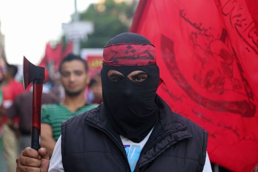 GAZA, Gaza City: A masked member of the Popular Front for the Liberation of Palestine holds an axe while participating in a protest in Gaza on October 20, 2015. The group is rallying against what it perceives to be Israeli aggression in Jerusalem, the occupied West Bank and Gaza region over the past month, during which an upsurge of violence, including stabbing and gun attacks, has led to the deaths of at least 37 Palestinians and seven Israelis.   
