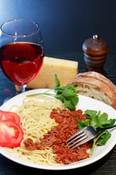 Traditional Italian supper. Plate with Bolognese pasta near red wine