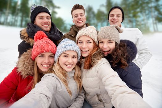 winter, technology, friendship and people concept - group of smiling men and women taking selfie outdoors