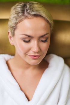 people, beauty, healthy lifestyle and relaxation concept - close up of beautiful young woman resting on chair in bath robe at spa