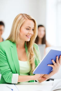 education concept - smiling young girl reading book at school