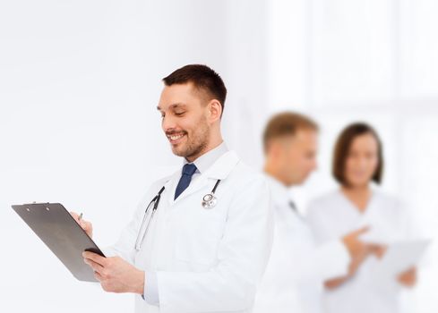 medicine, profession, and healthcare concept - smiling male doctor with clipboard and stethoscope writing prescription over white background