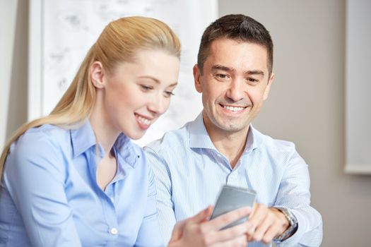 business, people, technology and teamwork concept - smiling businessman and businesswoman with smartphones meeting in office