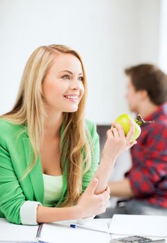 education concept - smiling student girl with green apple in college
