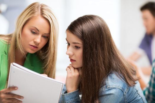 education concept - student girls looking at notebook at school