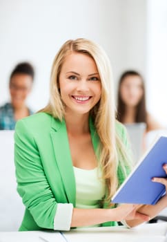 education concept - smiling young girl reading book at school