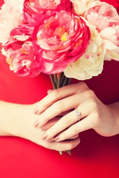 woman hands with bouquet of flowers and wedding ring.