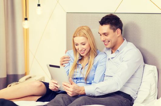 business, internet and technology concept - couple with tablet pc computer in hotel room