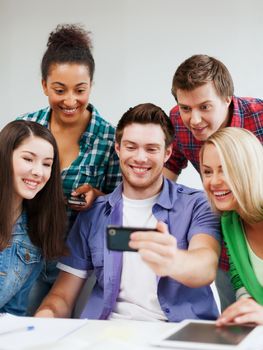 education concept - group of students looking into smartphone at school