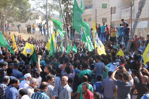 PALESTINE, Hebron: Violence continued in Hebron, Palestine on October 21, 2015 as Palestinians' held a funeral service for a fallen man. People gathered at the funeral wave flags.Hebron was the latest scene of violence as an IDF soldier was stabbed by an attacker on Tuesday. The attacker was shot and killed after the stabbing. 