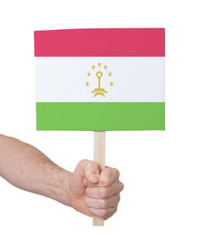 Hand holding small card, isolated on white - Flag of Tajikistan