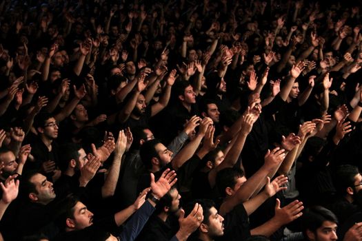 IRAN, Tehran : Hundreds of Shia Muslims raise their arms in Reyhane-Al-Hossein complex building for mourning session in tribute to imam Husayn ibn Ali on October 21, 2015, the 8th night of Muharram. one of the holy months in the Islamic calendar in Tehran, Iran. 