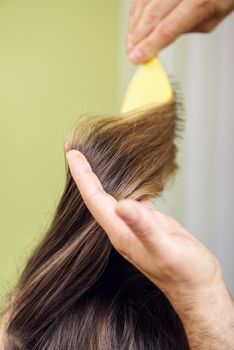 Hairdresser drying long brown hair with brush. 