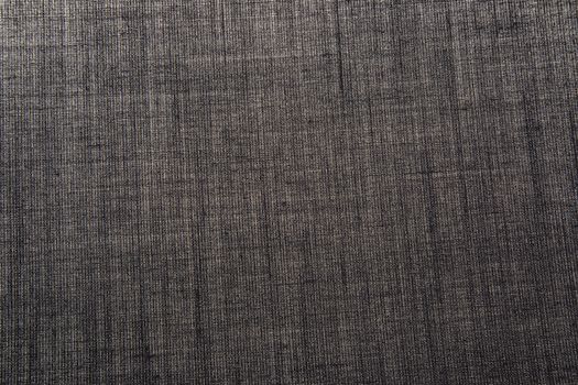Sheet dark gray cotton material with a distinct texture lit from below.Horizontal view.