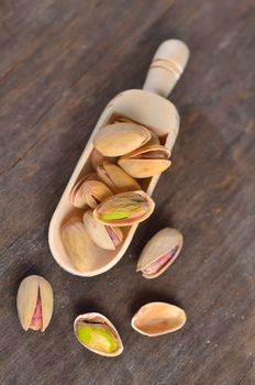 spoon of raw pistachio nuts on a old wooden background