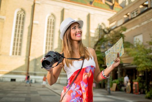 Young woman on vacation walking and studying map of city.