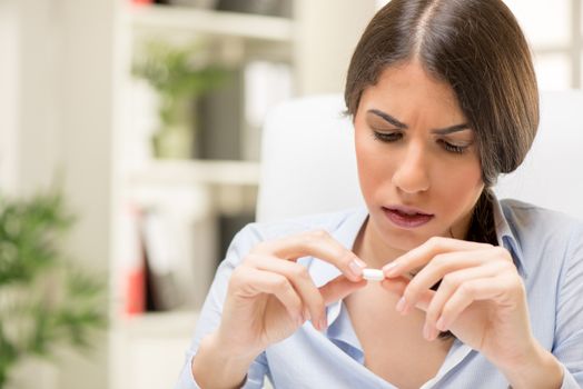 Young beautiful stressed woman takes a pill in the office.