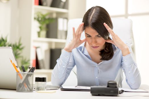 Portrait of a frustration young businesswoman sitting in the office and looking at document.