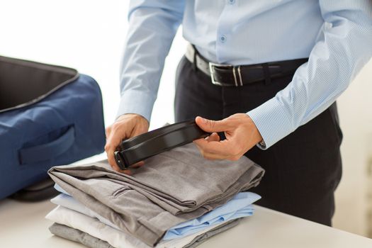 business, trip, luggage and people concept - close up of businessman packing clothes into travel bag