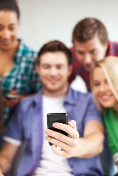 education and internet - smiling students looking at smartphone