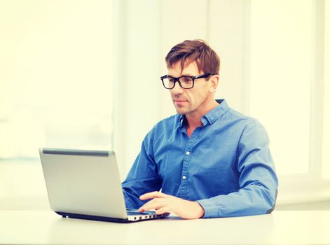 technology, business and lifestyle concept - man in eyeglasses working with laptop at home