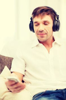 technology, leisure and lifestyle concept - happy man with headphones listening to music at home