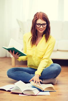 education and home concept - smiling student girl in eyeglasses reading books at home