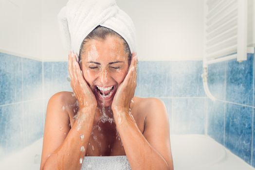 Beautiful girl washing the face with water in the bathroom.