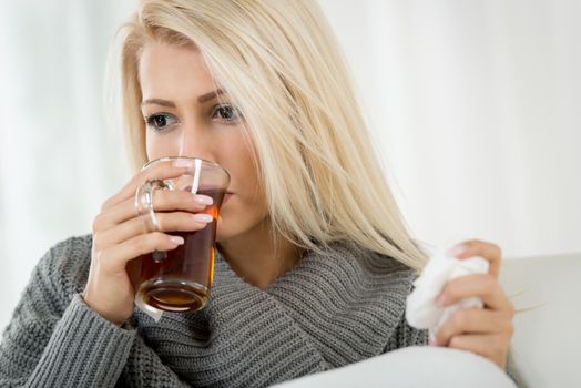 A beautiful girl drinking a tea and holding a handkerchief.