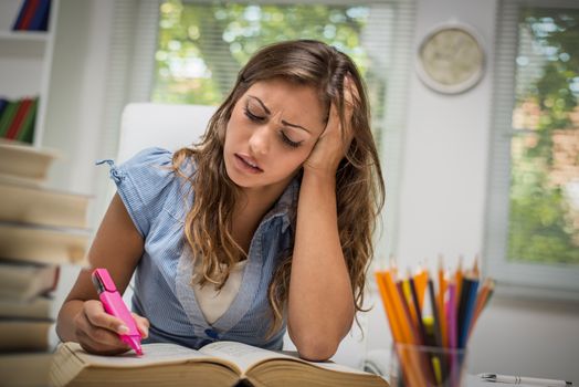 Tired beautiful teenage girl with many books learning in the library.