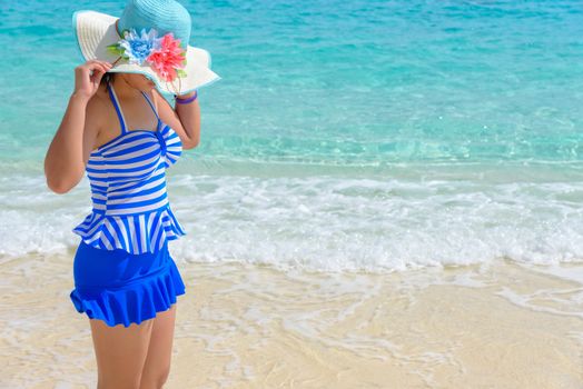 Tourist girl in a blue white striped swimsuit standing with happiness on the beautiful beach and sea during summer at Koh Miang Island, Mu Ko Similan National Park, Phang Nga province, Thailand