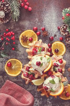 Homemade  waffles with  cranberries served with orange ice cream in a Christmas setting.  Top view, blank space, vintage toned