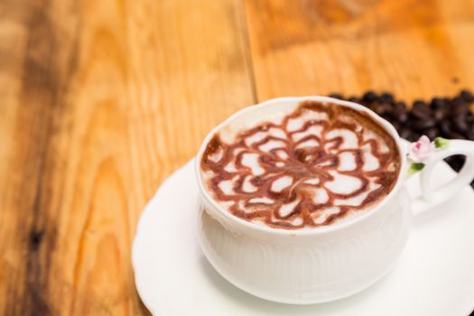 Milk foam coffee cup in white on a wooden floor.