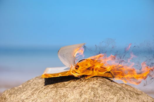 Book in fire flames on the sea coast