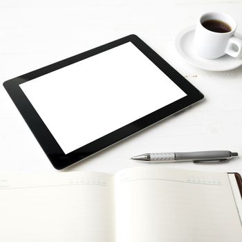tablet with office supplies over white table