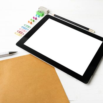 tablet with office supplies over white table