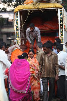 Pune, India - October 21, 2015: A man unloads his marigold flower sacks to small sellers after auctioning them on the eve of Dassera festival in India in which these flowers are traditionally used.