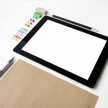 tablet with office supplies over white table