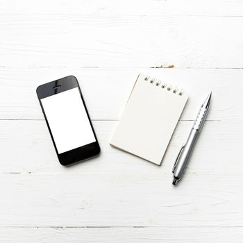 cellphone with notepad and pen over white table