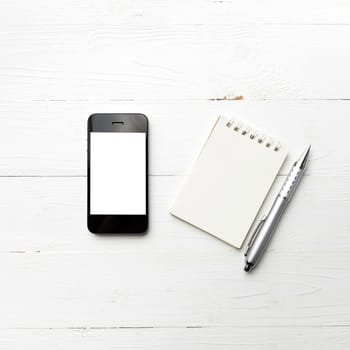 cellphone with notepad and pen over white table