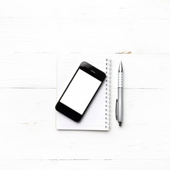 cellphone with notepad and pen over white table