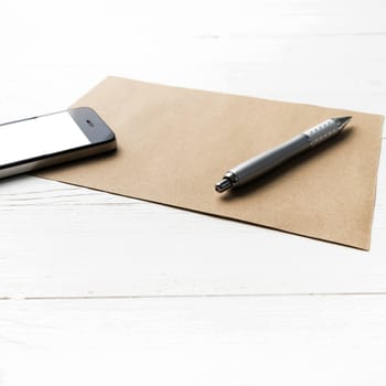 cellphone with brown paper and pen over white table