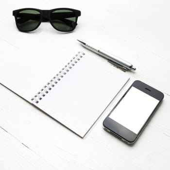 cellphone with notepad and pen over white table
