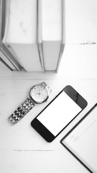 cellphone with stack of book and watch over white table black and white tone color style