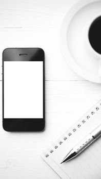 cellphone with notebook and coffee cup over white table black and white color style