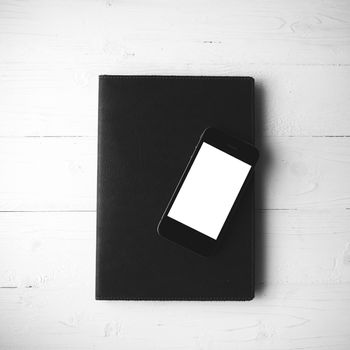 cellphone and notebook over white table black and white color style